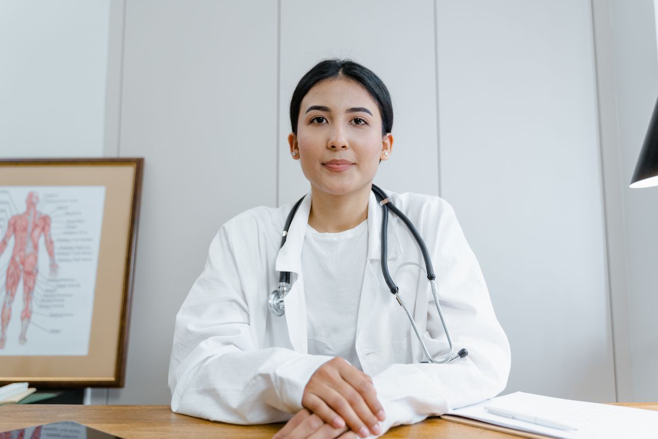 Home A female doctor confidently sits at her desk, ready for consultation in a medical office.