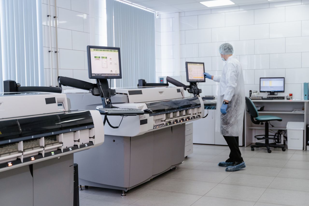 Home Scientist in a lab gown interacting with equipment in a modern laboratory setting.